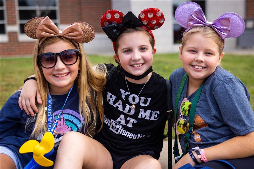Three girls smile while watching a parade
